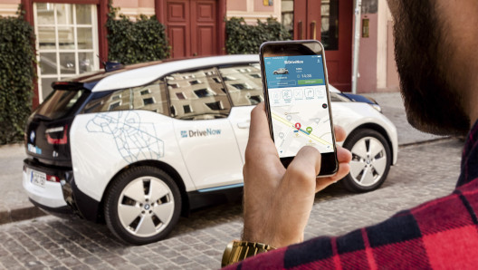 Ein junger Mann öffnet DriveNow BMW i3 mit dem Smartphone